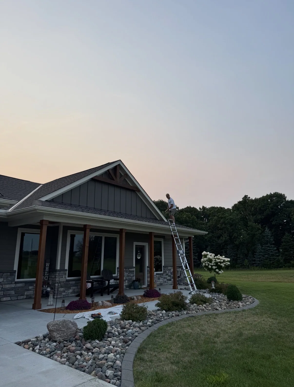 Exterior work in progress near the roofline of a gray house at dusk.