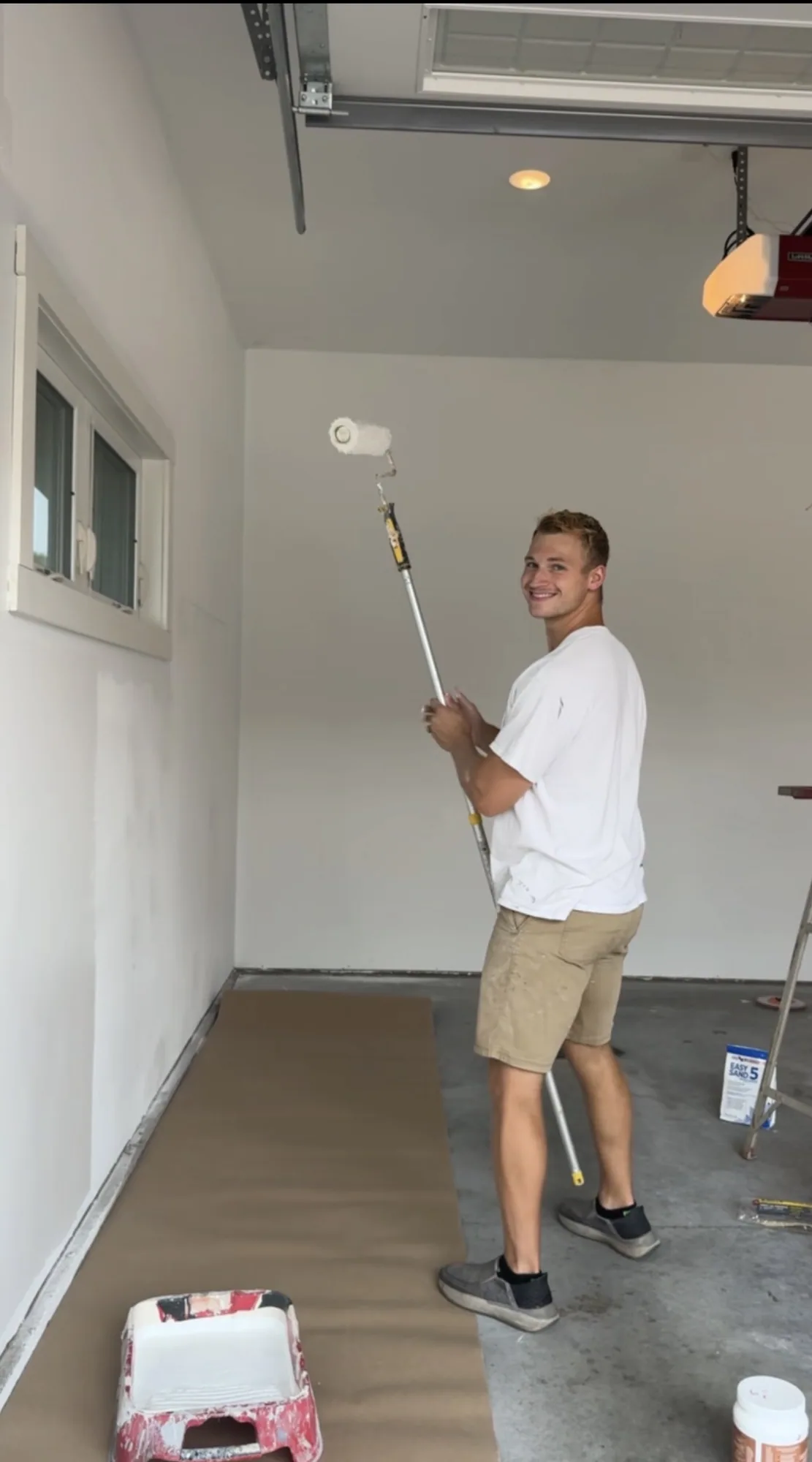 Me smiling while using a roller on a garage wall.