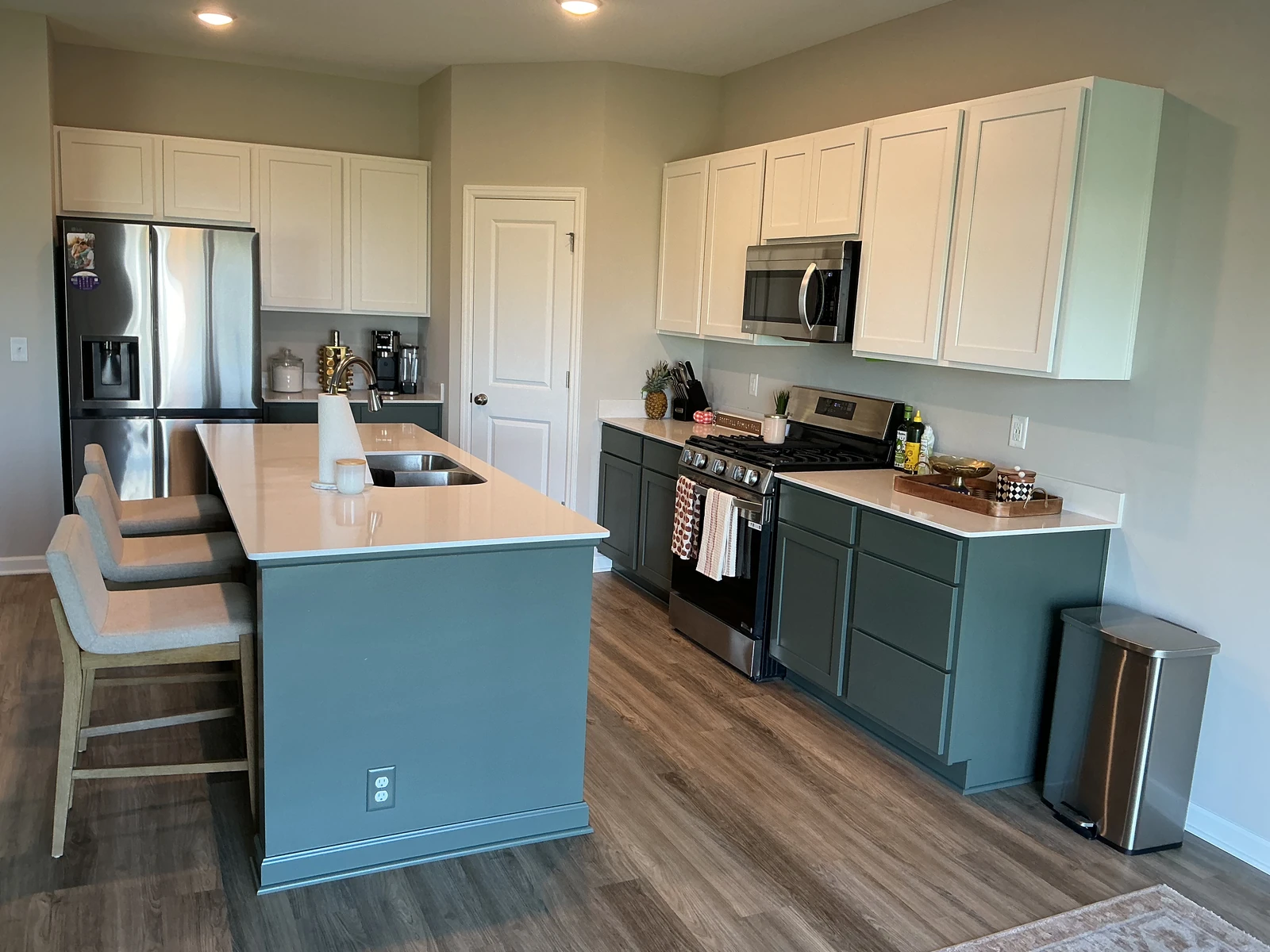 Finished kitchen with Pewter Green base cabinets and island, white upper cabinets, and white countertops.
